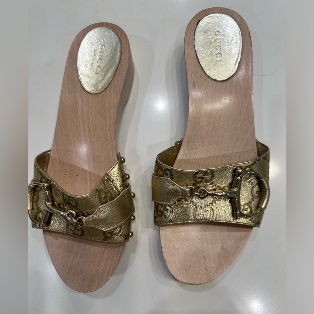 Gucci Sandals with wooden heel and gold bar across toes.